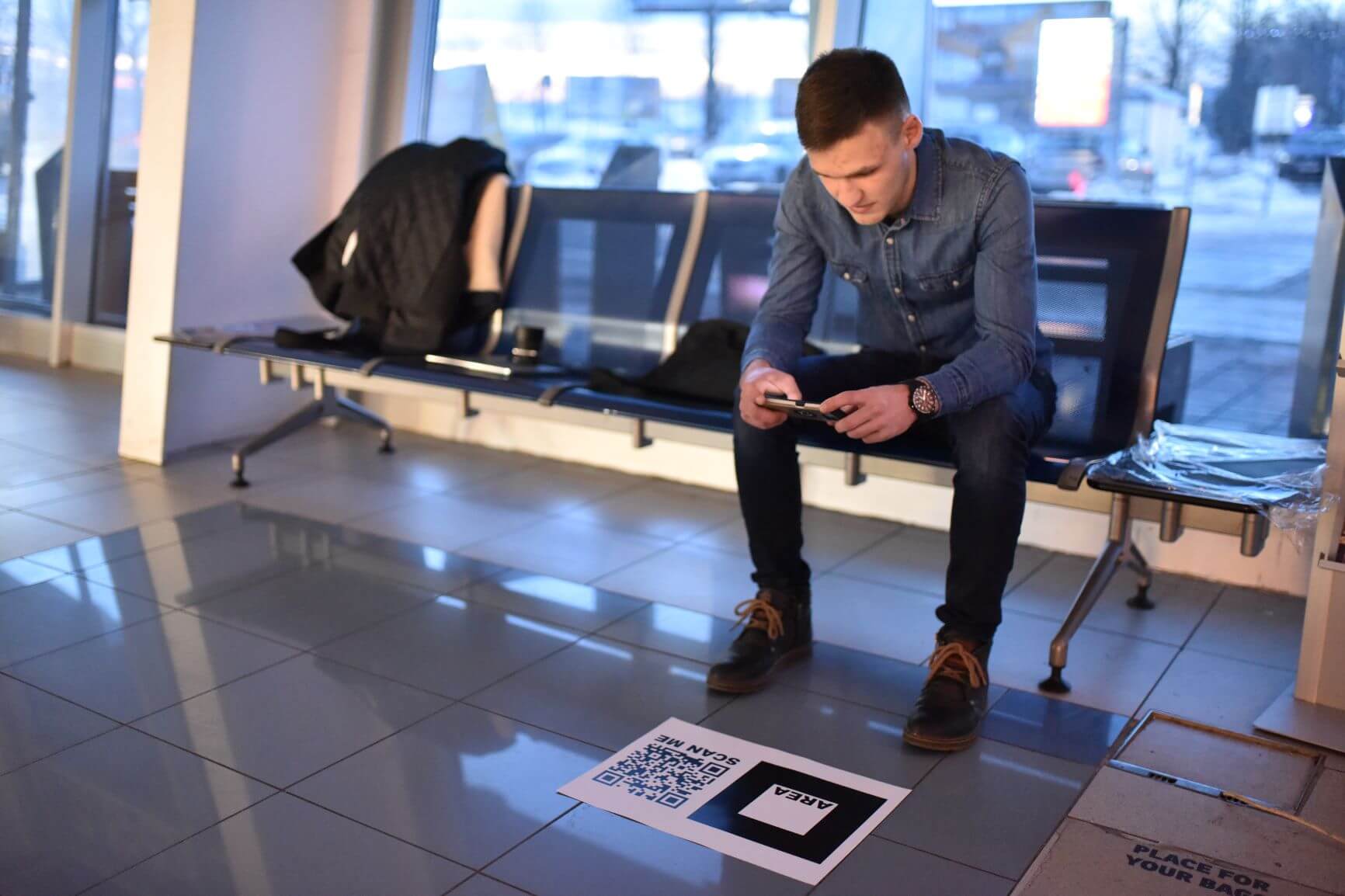 Guy sitting at an airport and playing tetris in an augmented reality